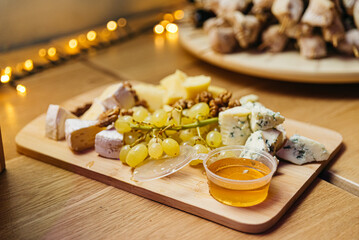 Cheese board with grapes and honey, catering at the event. Large pieces of moldy cheese.