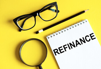 REFINANCE text on a paper with office tools, business concept