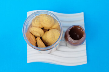 Mini biscuits in a jar topped with Cadbury chocolate sauce in a small jar on a blue background