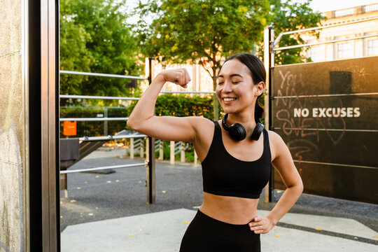 Young asian woman smiling and showing her bicep on playground