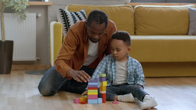 Games and education. Loving african american dad exercising with little son, playing wooden development toy, free space