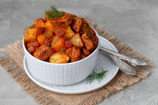 Pork and vegetable stew. Homestyle Pork ragout with tender pork, carrots and potatoes, cooked in a juicy tomato sauce and served in a bowl with fresh dill. Selective focus, horizontal.