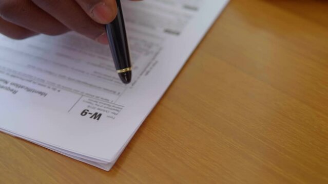 black man's hand ticking pen on the taxpayer application form