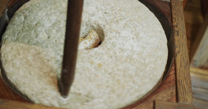 The baker grinds grain into flour. Antique hand mill in operation with an authentic 200 year old millstone