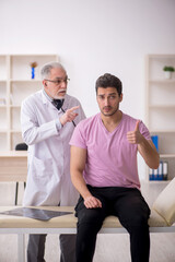 Fototapeta premium Young male patient visiting old male doctor