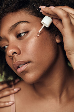 Black woman applying serum on face