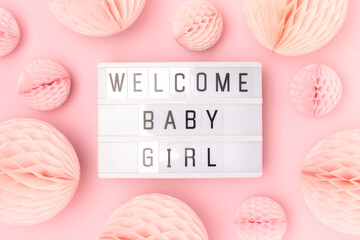 Welcome baby girl. Lightbox with letters and tissue paper balls in a pink color. Festive composition.