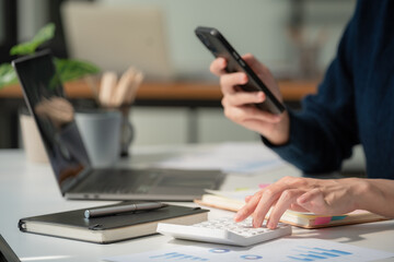 Fototapeta premium Close-up portrait of businesswoman accountant using calculator and laptop for matching financial data saving in office room, Business financial, tax, accounting concept