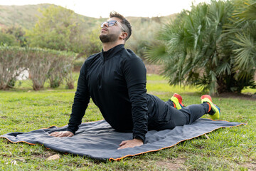 Young woman stretching on the grass of a park after practicing sports.