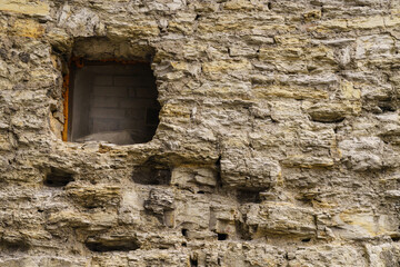 Fragment of an antique stone wall with a narrow window.