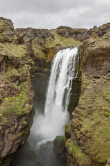 Waterfall on Laugavegur trek in Iceland. Dramatic icelandic landscape on cloudy day. Vertical photo.