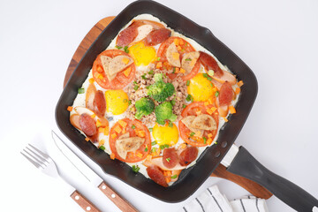 Fast food breakfast, fried eggs in pan and vegetables, top view