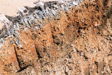 A footprint on the ground from the excavator bucket. A trench for repair work. Earthworks during road repairs. Repair of communications.