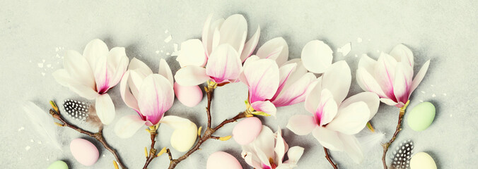 Easter banner with beautiful spring magnolia flowers and Easter decoration on grey stone background. Easter concept