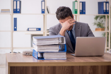 Obraz premium Young male employee and too much work in the office