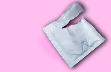 Condom on pink background. Flat view, from above. The concept of safe sex.