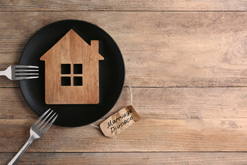 Divorce concept. Plate with model of house and forks near paper card on wooden table, flat lay....