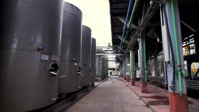 Many rows of medium-sized steel tanks (containers) for wine at a winery. Travelling forward shot.
