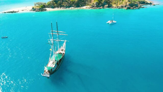 Overhead aerial view of a sailing ship arriving at island destination