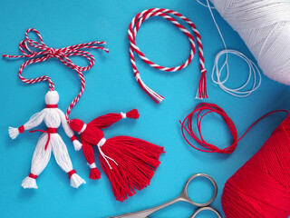 Martisor, red and white dolls shaped as man and woman on a blue background.