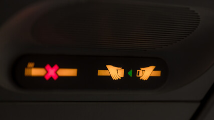 Prohibition signs in airplane light up signal that shows crossed cigarette and recommendation to...