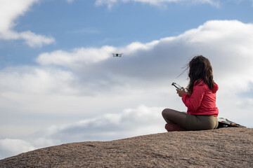 Girl Flying drone, sitting on a rock