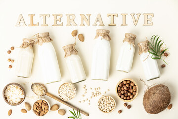Non dairy plant based milk in bottles and ingredients on light background with wood letters....