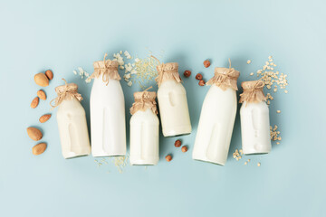 on dairy plant based milk in bottles and ingredients on turquoise background. Alternative lactose...