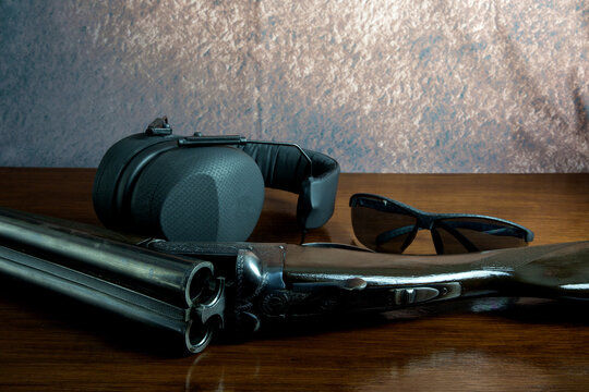 Old Shotgun with Ear Defenders and Safety Glasses on a Wooden Table Top