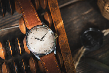 Vintage men's Omega dress watch with white dial and brown leather strap laying on the brown wooden...