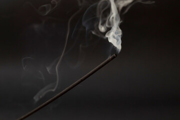 Incense stick smoking on a black background
