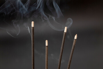 Burning aromatic incense sticks with fume on black background