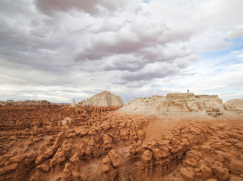 Hikers stand on the summit of a high mesa overlooking the vast field of hoodoos at Goblin Valley State Park, Utah.