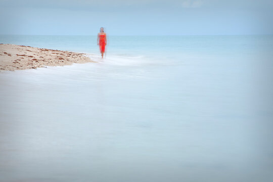 A woman walks along the beach on Coombe Island, Queensland, Australia.