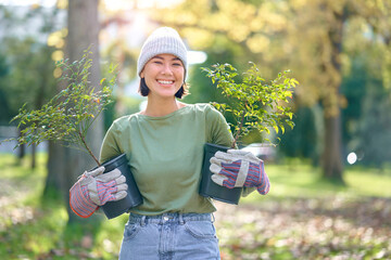 Woman portrait, plant and gardening in a park with trees in nature environment, agriculture or garden. Happy volunteer planting for growth, ecology and sustainability for community on Earth day