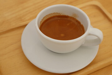 Espresso coffee in white ceramic cup on wooden table background. 