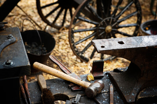 An anvil, hammer and tools in oldtime setting.