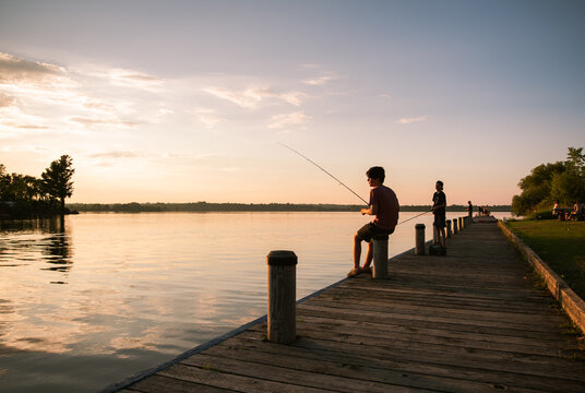 Boys fishing on the dock of a lake at sunset in Ontario, Canada.