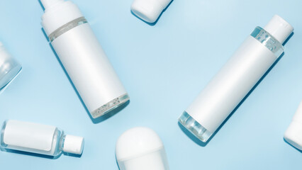 White natural cosmetic products, bottles and tubes with branding mockup on blue table background, top view, flat lay. Facial care and beauty