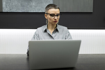 Business woman in glasses working on a laptop in a stylish office