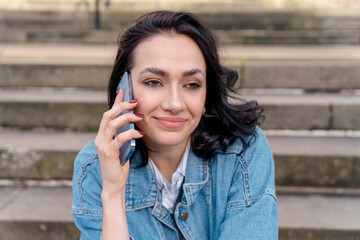 Outdoor portrait of an happy  young woman in a denim jacket is talking on the phone  Lifestyle photo