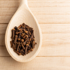 Cloves in wooden spoon on the wooden background