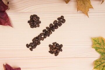 Sign is the percentage. Mathematical sign denoting - percentage. Collected from roasted coffee beans on a wooden textured countertop. Thin diagonal line. Autumn leaves lie around