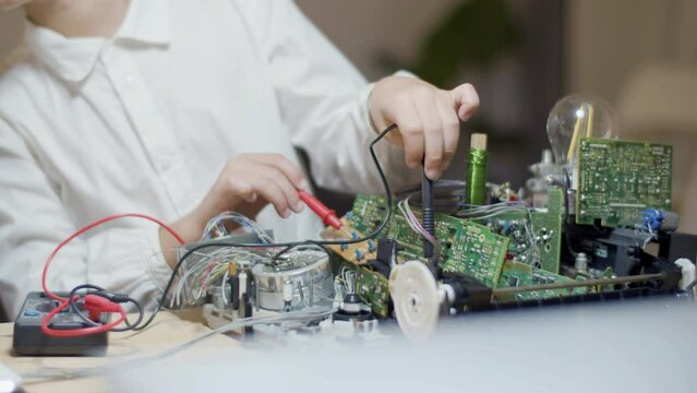 Caucasian child measuring electric current in circuit board set. Close-up shot of secondary school student using ammeter for testing flow of electricity in circuit board. Education, hobby concept