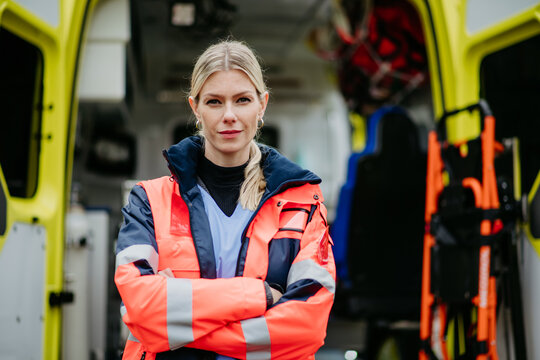 Portrait of young woman doctor standing in front of ambulance car.