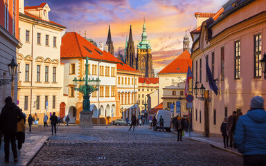 Fototapeta premium Prague, Czech Republic. Picturesque street of old town. View to Saint Vitus Cathedral tower with spires. Evening sunset