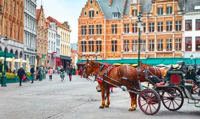 Poster Bruges, Belgium. Market Square (Markt. Historical centre of old town. Carriages with horses waiting for touristic rides and city tours © Yasonya