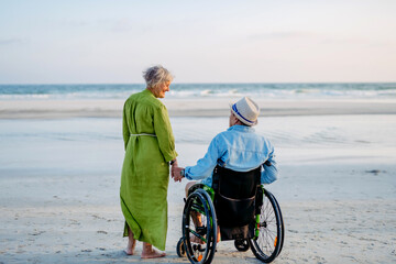 Senior man on wheelchair enjoying together time with his wife at sea.