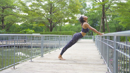 Portrait of Black African American woman in yoga class club doing exercise, runing or jogging at public garden park. Outdoor sport and recreation. People lifestyle activity with nature trees view.
