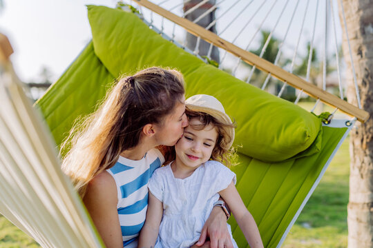 Mother with her daughter enjoying holiday in exotic country, lying in hammock.